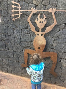 Ein kleines Kind steht vor dem aus Stahl gefertigten Feuerteufel des Nationalparks Timanfaya auf Lanzarote.