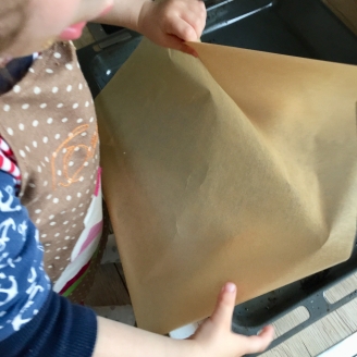 Ein Kind legt ein Backblech mit Backpapier aus.